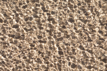 Small ripples and waves in sea on water above sand and bottom. Natural texture, surface with copy space.