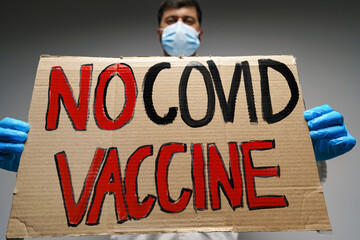 Doctor holding protest banner with 'no COVID vaccine' text