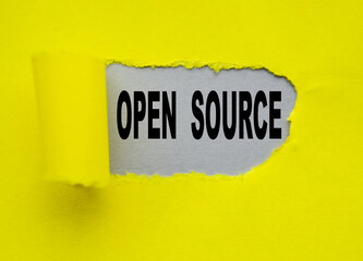 Open source text is visible through a hole in the yellow paper, on a gray background. A concept...