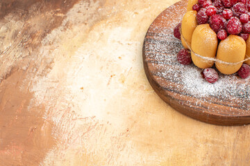 Half shot of homemade soft cake with fruits on wooden cutting board on mixed color table