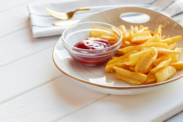 French fries potatoes in plate with sauce on wooden table