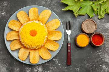 top close view of salad on left side with herbs fork and leaves on side on dark grey table