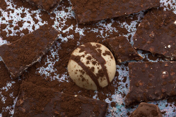 Broken almone chocolate pieces with cocoa powder.