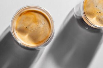 Americano coffee in glass cups on white background with long shadows