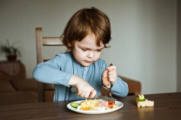 Cute boy eating dinner at home.