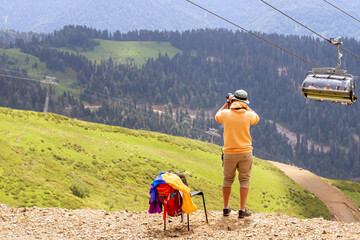 Man make a photo of chairlift in a mountain region in summer