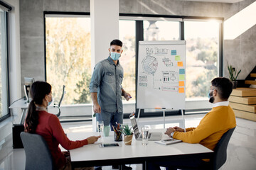 Freelance worker giving business presentation to his colleagues in the office during coronavirus pandemic.