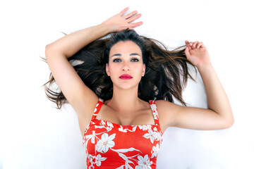 beautiful brunette woman lying on her back looking at the camera with her arms above her head and...