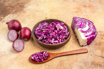 Obraz na płótnie Canvas top view a bowl of chopped red cabbage and several red onions for vegetable salad on a wooden background with copy place