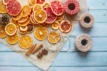 cinnamon, anise, dried oranges and grapefruit slices, threads for diy projects, gift wrapping and beautiful eco Christmas decorations like wreaths arranged on a blue wooden table - 400151245