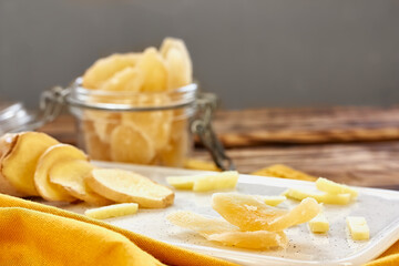 Candied ginger slices in a white plate on wooden table. Dehydrated oriental fruits. Healthy sweets....