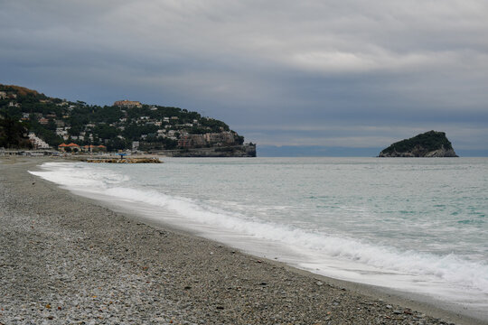 La spiaggia di Spotorno con il promontorio e l'isolotto di  Bergeggi in una giornata nuvolosa di Dicembre