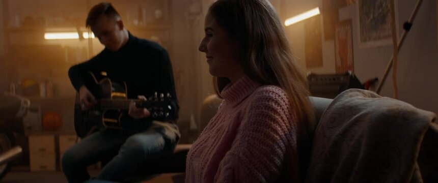 Teenager boy playing guitar to a girl he likes. New relationship start. Hesitate, love, teen life. Shot with 2x anamorphic lens