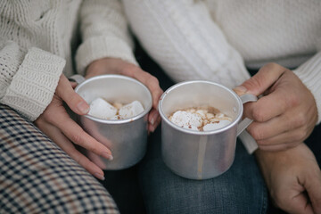 Happy couple drinking hot cocoa sitting in a van decorated with festive Christmas lights.