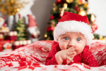 Christmas time. Beautiful little baby boy dressed as Santa celebrates Christmas. Bokeh background.