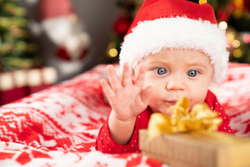 Christmas time. Beautiful little baby boy dressed as Santa celebrates Christmas. Bokeh background.