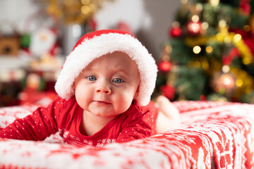 Christmas time. Beautiful little baby boy dressed as Santa celebrates Christmas. Bokeh background.