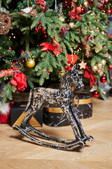 a black wooden horse with scuffs stands under the Christmas tree