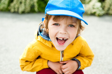 A cheerful child in a blue cap laughs merrily.