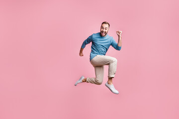 Fototapeta na wymiar Full length photo of funny charming young man dressed blue sweater jumping high running fast isolated pink color background