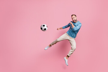 Fototapeta na wymiar Full length photo of sweet strong young man dressed blue sweater jumping high kick foot ball isolated pink color background