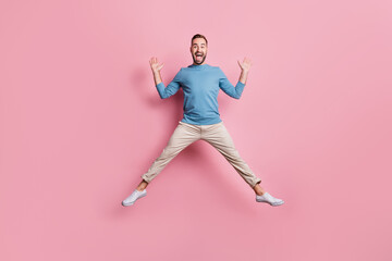 Fototapeta na wymiar Full length photo of charming cute young man dressed blue sweater jumping high like star isolated pink color background