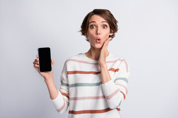 Photo of surprised young lady wear striped sweater pointing holding modern gadget arm cheek mouth isolated grey color background