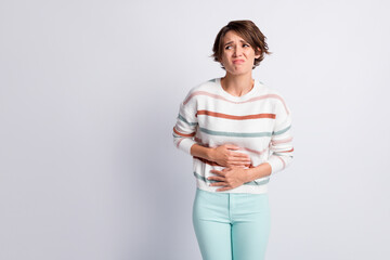Photo of sad young lady wear striped sweater arms tummy having period looking empty space isolated...