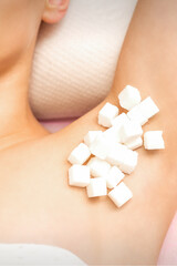 Sugaring concept. White sugar cubes lying on the armpit of a young female