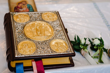 Holy Bible decorated with gold and icons lies on the table in church. Close up.