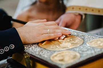 Newlyweds hold hands, couple at the wedding ceremony in the church. The priest blesses the holy...