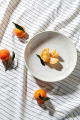 food, healthy eating and fruits concept - close up of mandarins on plate over drapery