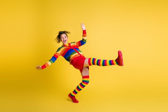 Full length photo of funky lady raise leg stand on toe bending wear striped sweater short skirt knee socks shoes isolated yellow color background