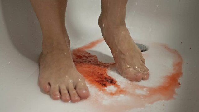 Women's feet in the shower. The water washes away the blood. Spontaneous miscarriage in the early stages.