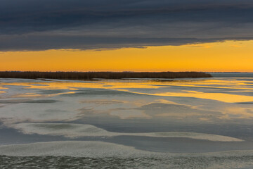 Fototapeta premium frozen lake with reed during sunset with rain clouds