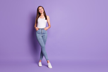 Full size photo of dreamy girl look empty space hold hands in pockets isolated on purple color background