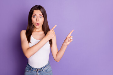 Fototapeta premium Photo of surprised charming young woman wear casual white outfit looking pointing two fingers empty space isolated violet color background