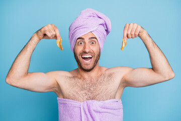 Portrait of nice cheerful guy wearing turban towel holding in hands hyaluronic facial patches hydraion isolated on bright blue color background