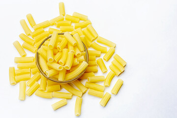 Uncooked raw Italian rigatoni pasta in a glass bowl on isolated white background.