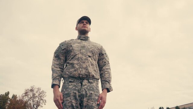 Low angle view of soldier saluting with sky at background outdoors