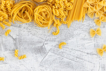 Various pasta on white stone background. View from above. Flat lay.