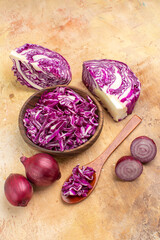 Fototapeta na wymiar top view several red onions and chopped red cabbage in a wooden bowl for beet salad on a wooden background with copy place