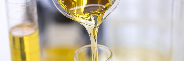 Golden liquid is poured from flask into test tube. Petroleum research and experiences concept