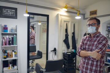 Hairdresser with surgical medical mask waiting for customers in a hair salon.