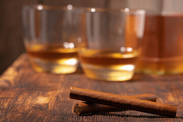 Two glasses of whisky and cigars on wooden table