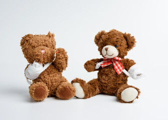 brown curly teddy bear with rewound paw with white gauze bandage on white background