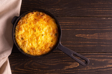 Frittata with cheese, mozzarella and stewed pumpkin in a cast iron pan on a wooden background