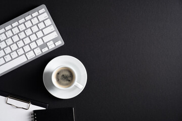 Black office desk table with computer keyboard, cup of coffee, clipboard, notepad. Luxury, minimalist style workspace. Flat lay, top view, copy space. Business concept.