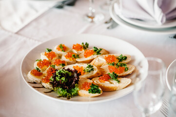 Sandwiches with red caviar and parsley on a plate.