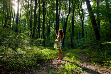 Naklejka na ściany i meble A pregnant woman is posing in the forest